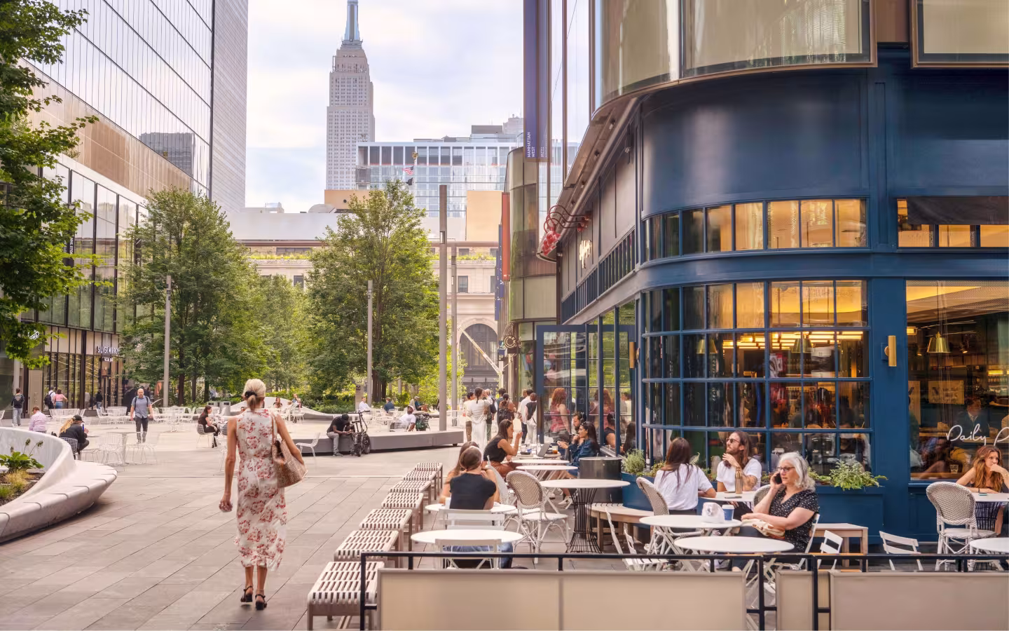 Exterior view of Daily Provisions at Brookfield Place New York, a BGRE office and retail destination in Lower Manhattan, featuring a pedestrian-friendly streetscape and outdoor gathering spaces with the NYC skyline beyond.